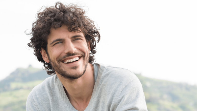 Outdoor portrait of a happy smiling man with curly hair